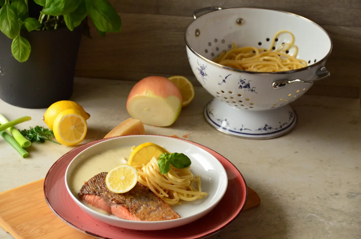 Gebratener Lachs mit Zitronenpasta vor Basilikum und einem Porzellansieb