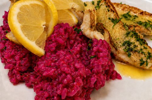 Pinkes Rote-Bete-Risotto mit gebratenem Fischfilet und Zitronenscheiben